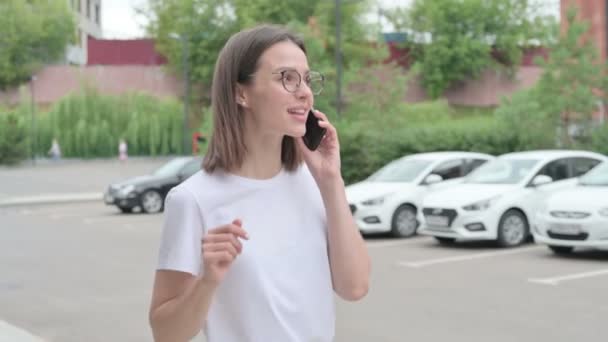 Young Woman Talking on Smartphone while Walking on Street — Stock Video