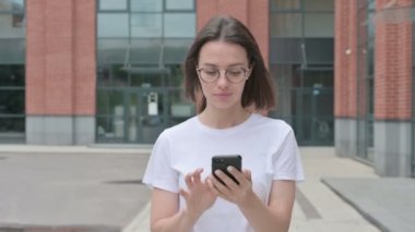 Genç Kadın Smartphone 'da internette gezinirken sokakta yürürken