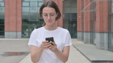 Genç Kadın Smartphone 'da internette gezinirken sokakta yürürken
