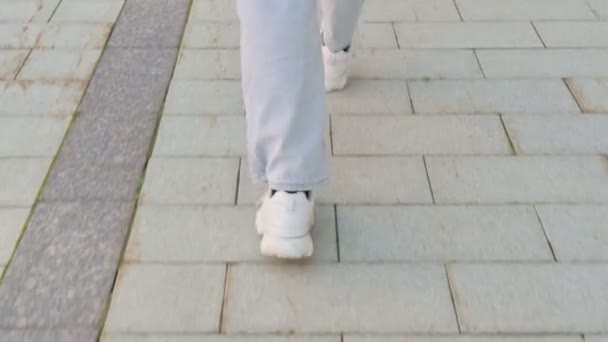 Close-up shot van voeten van jonge vrouw wandelen op pavement, terug te zien — Stockvideo
