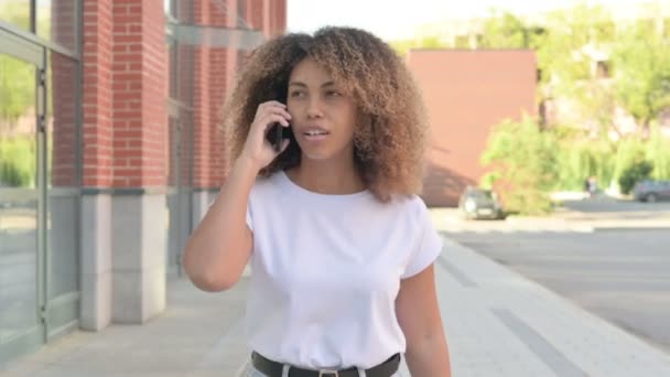 Mulher Africano irritado falando em Smartphone enquanto caminhava ao ar livre — Vídeo de Stock