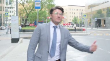 Orta yaşlı işadamı otobüs durağında asansör istiyor.