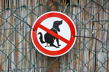 Yuvarlak kırmızı ve beyaz tabela, silueti çizilmiş kaka yapan köpek. 