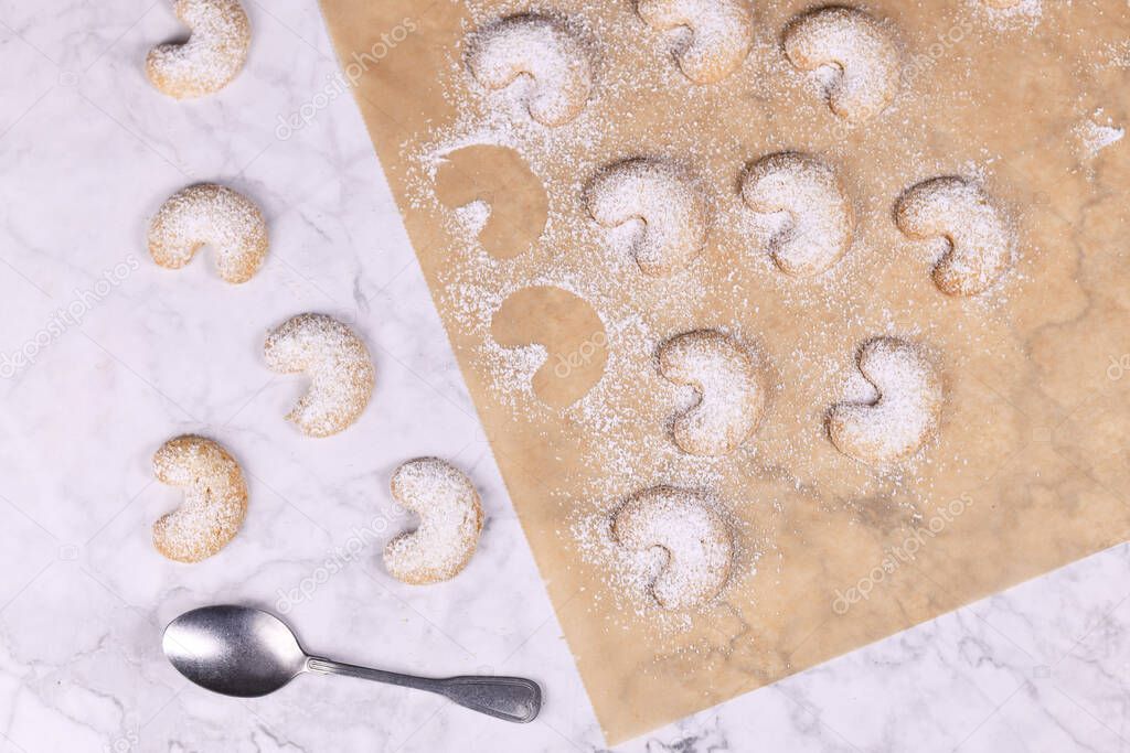 Crescent shaped christmas cookies called 'Vanillekipferl', a traditional Austrian or German Christmas biscuits with nuts and icing sugar on baking paper