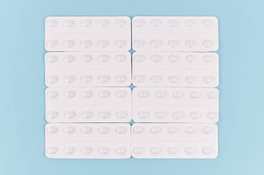 Mavi arka planda beyaz hap paketleri yan yana dizildi