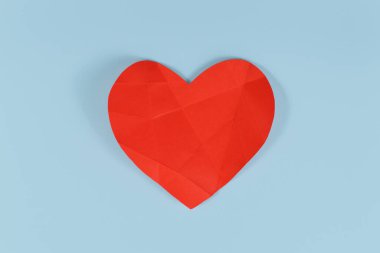 Kırık kırmızı kağıt kalp ve mavi arka planda katlanmış çizgiler. Kırık ya da hasta kalp kavramı