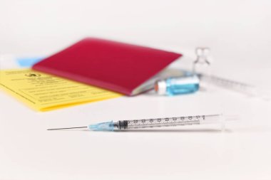 Corona virüsü aşısı olmayanlar için seyahat kısıtlaması kavramı şırıngası ve aşı sertifikası ile bulanık arka planda seyahat pasaportu