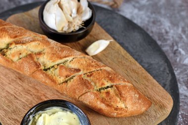 Taze baget ekmeği pişmiş ve ahşap kesim tahtasına tereyağıyla doldurulmuş.