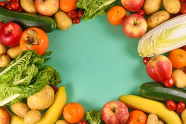 Yeşil arka planda boş fotokopi alanı olan çeşitli sağlıklı çiğ meyve ve sebzeler