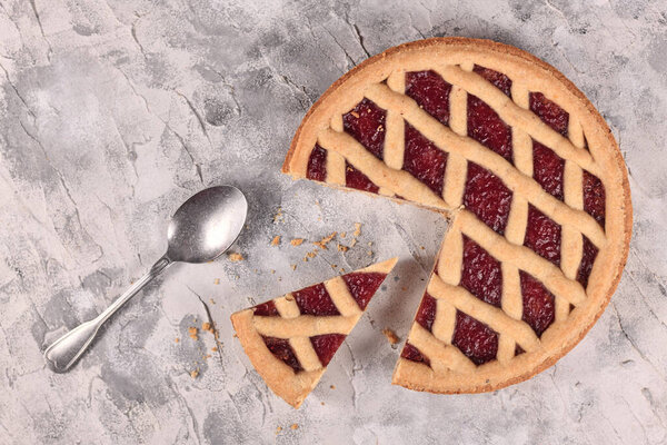 Whole pie called 'Linzer Torte', a traditional Austrian shortcake pastry topped with fruit preserves and sliced nuts with lattice design with slice cut out