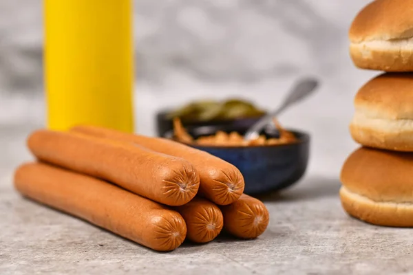 Sausages for making homemade hot dogs with ingredients like buns, dried onions and mustard