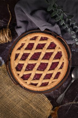 'Linzer Torte' adlı ev yapımı turtanın en üst görüntüsü, üzerinde meyve reçelleri ve kafes tasarımlı dilimlenmiş fındıklar olan geleneksel Avusturya pastası. 