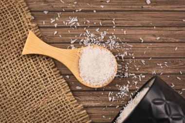 Küçük tahta kaşıkta kurutulmuş hindistan cevizi taneleri. 