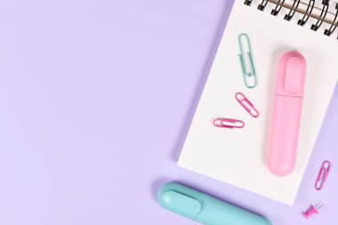 Pembe ve mavi metin işaretleyicili pano ve mor arkaplan üzerinde boş kopya alanı olan ataçlar