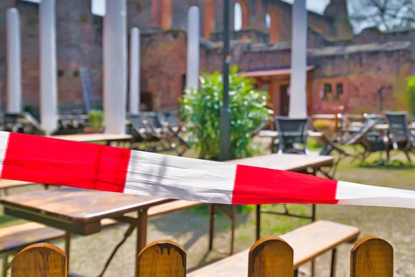 Striped barrier tape blocking off closed beer garden restaurant during Corona Virus lockdown