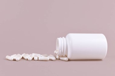 Medical capsule pills spilling from blank container