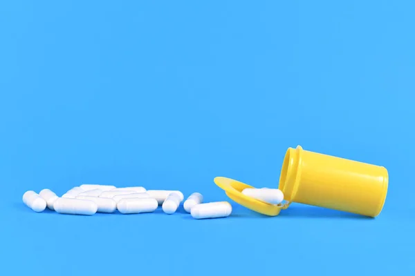 Vita Kapsel Piller Spillning Från Gul Läkemedelsbehållare Klarblå Bakgrund — Stockfoto