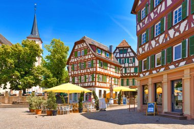 Mosbach, Almanya - Haziran 2021: Güneşli bir günde tarihi şehir merkezinde pazar yerinde boş masaları ve geleneksel kereste çerçeveli evleri olan kafe 