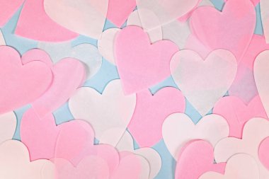Açık mavi arkaplanda pembe ve beyaz kalp şeklinde kağıt konfeti