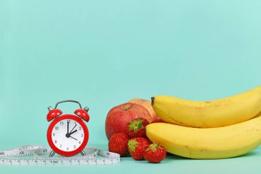 Meyveli diyet kavramı, mezurası ve kopya alanı olan gök mavisi arkaplan üzerindeki saat