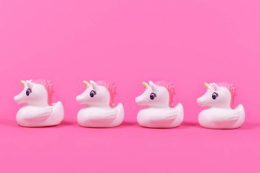 Pembe arka planda dört sevimli lastik ördek tek boynuzlu atı