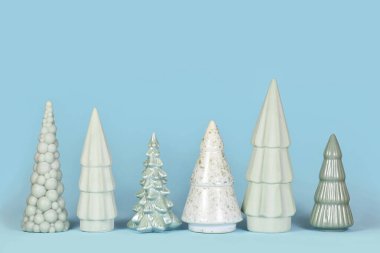 Mavi arka planda farklı şekilli açık yeşil seramik Noel ağaçları.