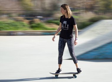 Siyah tişörtlü, kaykay yapan genç bir kız. Hareketli resim