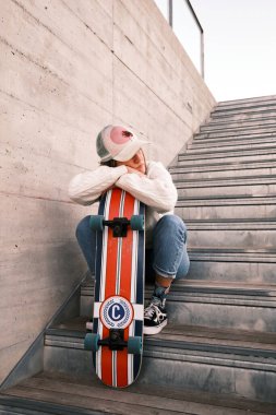 Merdivende oturan kaykaylı genç bir kadın.