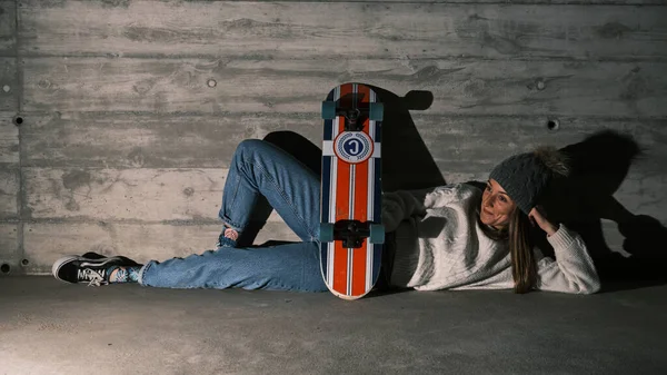 Молодая женщина лежит на полу со скейтбордом — стоковое фото