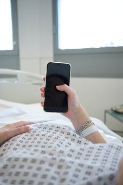 Hastanede damlayan hamile kadın akıllı telefonunu kullanıyor.