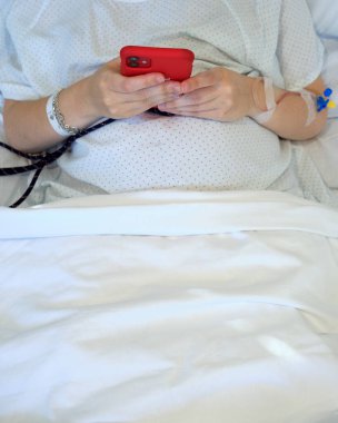 Hastanede damlayan hamile kadın akıllı telefonunu kullanıyor.