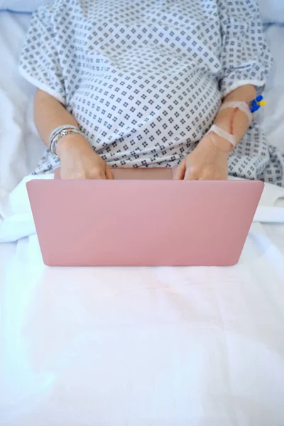 Беременная женщина на капельнице в больнице с помощью ноутбука — стоковое фото