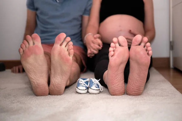 Przyszłe stopy mamy i taty w małych bucikach. Pojęcie rodzicielstwa — Zdjęcie stockowe