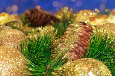 Parlak sarı Noel topları ve ağaç kabukları ve çam dalları olan koniler. Bokeh 'in mavi arka planı. Yeni yıl kartı. Boşluğu kopyala