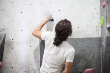 Genç, formda bir tırmanıcı kaya duvarına tırmanıyor, içerideki yapay duvara tırmanıyor..