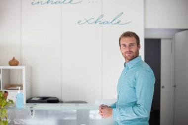 Modern fitness kulübünün resepsiyonunda maske takan genç adam.