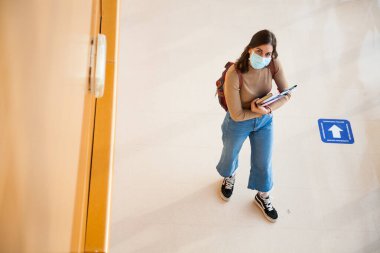 Coronavirus döneminde maske takan genç bir üniversite öğrencisi.