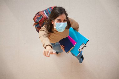 Coronavirus döneminde maske takan genç bir üniversite öğrencisi.