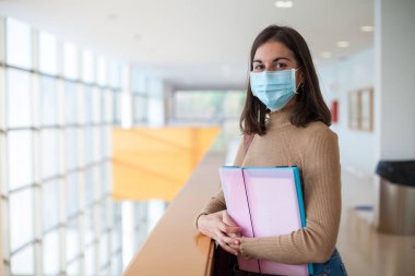 Coronavirus döneminde maske takan genç bir üniversite öğrencisi.