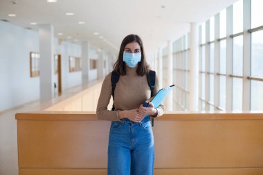Coronavirus döneminde maske takan genç bir üniversite öğrencisi.