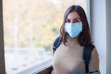 Coronavirus döneminde maske takan genç bir üniversite öğrencisi.