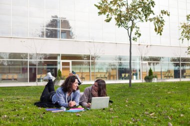 İki mutlu üniversite öğrencisi okul kampüsünde çalışıyor.