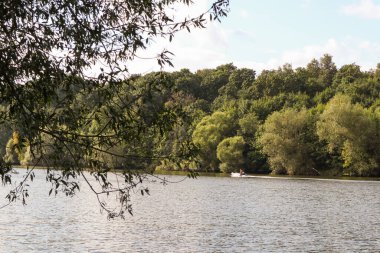 Bir adam gün batımında nehir boyunca bir motorla şişme bir teknede yüzer.