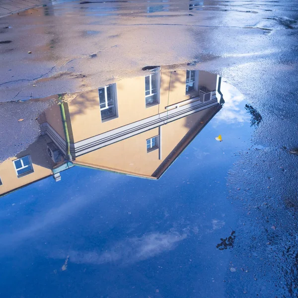 Reflection of the autumn sky and the house in a puddle after a thunderstorm — Stock Photo, Image