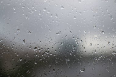 Pencere camında küçük ıslak yağmur damlaları. Rutubetli, yağmurlu, üzücü hava. Şehrin bulanık dış hatları