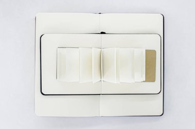 Birbirinin üzerine açılmış iki defter ve boş bej sayfalı bir yelpaze. Kitap piramidi. Üst Manzara. Beyaz arkaplan