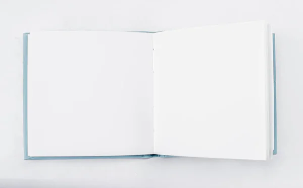 Küçük, kare şeklinde, açık bir defter, arkaplanda boş beyaz sayfalar olan bir kitap. Üst Manzara. Şablon