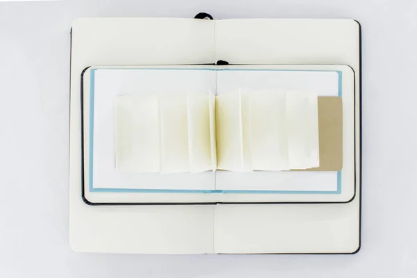 3つの展開ノートブックは お互いの上に位置し 空白のライトベージュのページを持つファンオープン小さなノートパッド 最上階だ — ストック写真