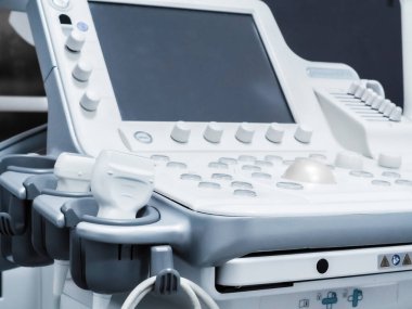Düğmeleri, monitörü ve sensörleri olan bir ultrason makinesi. Beyaz gri renkli modern tıbbi ekipmanlar. Ayrıntılar. Yakın plan.