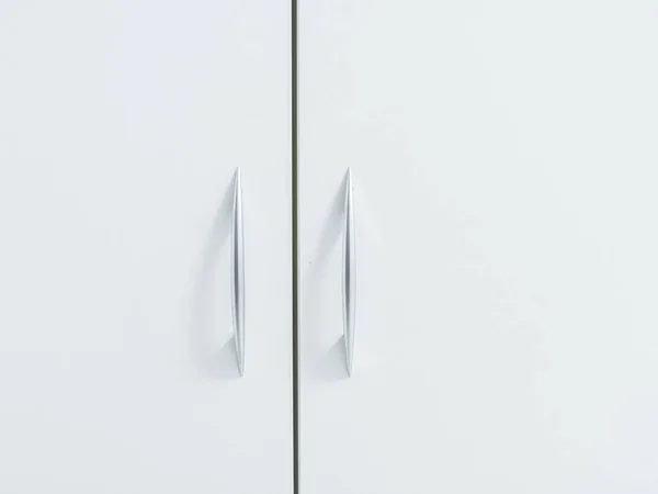 White cabinet doors with thin metal handles. Minimalistic light cupboard. Close-up